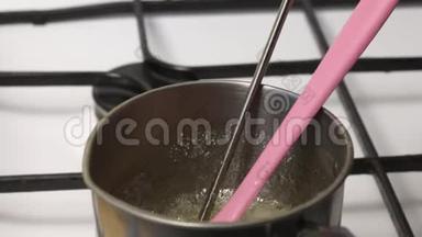 一个人把温度计放在糖浆里测量它的温度。 糖浆在炖锅里煮，准备棉花糖。 可见厚